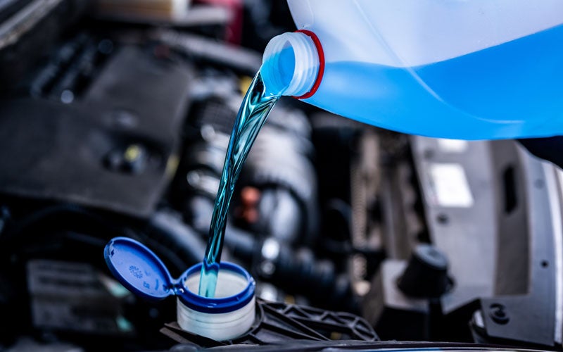 Blue coolant being poured into car engine